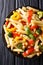 Close-up of Italian vegetarian penne pasta with chickpeas, broccoli, bell pepper and spices in a plate. Vertical top view