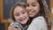 Close-up of joyful charming schoolgirls friends hugging and smiling looking at camera. Happy friendly African American