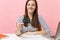 Close up of joyful woman in casual clothes holding credit card work sit at white desk with contemporary pc laptop