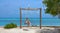 CLOSE UP: Joyful woman swings on the scenic swings on a tropical sandy beach