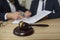 Close up of judge's gavel on table, and lawyer giving consultation in background