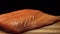Close-up of juicy piece of salmon. Juicy fresh and red slice of salmon meat lying on wooden board on black background