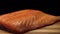 Close-up of juicy piece of salmon. Juicy fresh and red slice of salmon meat lying on wooden board on black background