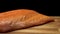 Close-up of juicy piece of salmon. Juicy fresh and red slice of salmon meat lying on wooden board on black background