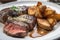 close-up of juicy and tender steak, with crispy potatoes on the side