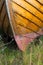 Close up of the keel of an old wooden boat on land with grass growing underneath it