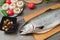 Close-up keta fish, whole on the cutting board of the kitchen table next to olives tomatoes and mushrooms. Healthy sea