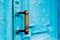 Close-up keyholes with curtains and a handle on the blue many times painted cracked double-barreled wooden vintage door