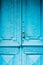 Close-up keyholes with curtains and a handle on the blue many times painted cracked double-barreled wooden vintage door