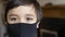 Close up kid face wearing medical face mask, Mixed race child boy with beautiful brown eyes looking at camera black face mask,