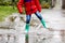 Close-up of kid wearing yellow rain boots and walking during sleet, rain and snow on cold day. Child in colorful fashion