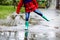 Close-up of kid wearing yellow rain boots and walking during sleet, rain and snow on cold day. Child in colorful fashion