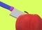 Close up of a kitchen knife slicing a red apple against a luminous green backdrop