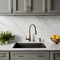 A close-up of a kitchen sink featuring grey cabinets, a white marble countertop, backsplash, and accents