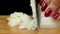 Close-up of a knife cutting white onion on a wooden board