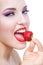 Close up of lady with red lips eating strawberry