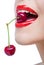 Close up of lady with red lips eating two berries