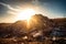 close-up of a landfill's towering pile of waste, with the sun shining down on it