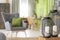Close-up on lanterns with candles on wooden stool in green living room interior. Real photo
