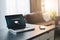 Close up of laptop with inscription on screen e-learning and image of square academic cap and smartphone on table in empty room.