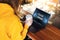 Close-up of laptop screen with inscription on monitor- cloud library. Rear view. Girl in yellow hoodie works on computer in cafe