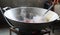 Close-up, large iron pan cooking, smoke and heat inside the kitchen.