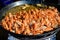 Close up of large portion of cooked shrimps with tomato sauce and yellow lemons in a large pan at a street food festival, ready to