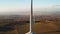 Close up a large spinning wind turbine on the background of wind farm at sunset.