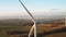 Close up a large spinning wind turbine on the background of wind farm at sunset.