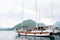 Close-up of a large yacht with deflated sails near the mountain of Perast.