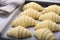 Close up of layered of a fluffy leavened uncooked traditional French croissants dough roll in a baking tray&paper sheet, preparing