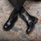 Close-up of leather fashionable autumn black boots with lacing on female legs. New stylish seasonal collection of women`s shoes.