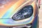 Close-up LED headlight expensive car part with exclusive iridescent painting. Vehicle covered with vibrant chameleon