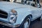 Close-up of the left headlight of retro grey cabriolet car with chrome mirror, disc, window trim and bumper, wheel arch