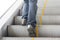 Close up leg of Men wear jeans, leather shoes. Standing on the escalator