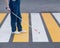 Close-up of the legs of a blind woman crossing the road at a crosswalk with a cane.
