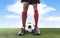 Close up legs feet football player in red socks and black shoes playing with ball on grass pitch outdoors
