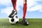 Close up legs feet football player in red socks and black shoes playing with ball on grass pitch outdoors