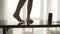 A close-up of legs of a girl dancing barefoot on the black kitchen table with a wireless speaker on the table