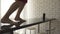 A close-up of legs of a girl dancing barefoot on the black kitchen table with a wireless speaker on the table