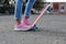 Close-up legs of girl skateboarder in blue jeans and pink sneakers, riding pink penny skate longboard.