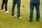 Close Up Of Legs Of Golfers Holding Clubs On Golf Tee