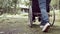 Close-up legs of granddaughter pushing grandfather in a wheelchair walking along the road enjoying nature in the park. Family life