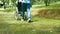 Close-up legs of granddaughter pushing grandfather in a wheelchair walking along the road enjoying nature in the park. Family life