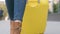 Close-up of the legs of a lady traveler with a yellow suitcase