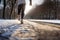 Close-up at legs of a male runner jogging in a park cover by snow.