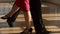 Close-up of the legs of a man and a woman dancing a pair of ballroom dance in the room. Dance moves of the tango.