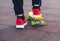 Close up legs in red sneakers riding on yellow skateboard in motion. Active urban lifestyle of youth, training, hobby,