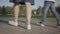 Close-up legs of siblings children walking holding hands in the summer park. Leisure outdoors. Friendly relations