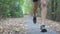 Close up legs of sporty man running along trail in early autumn forest. Male feet of young athlete jogging along path at